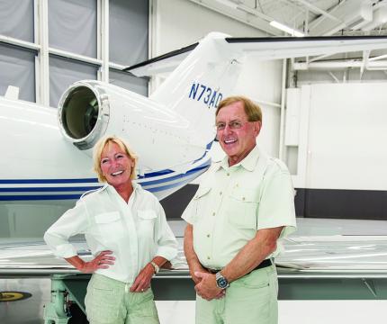 Donors Fred Kaiser and Grace Borsari standing in front of an airplane tail